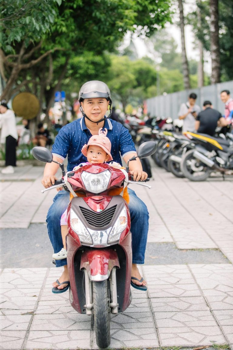 A father and his child enjoy a scooter ride together on a sunny day, showcasing happiness and bonding.
