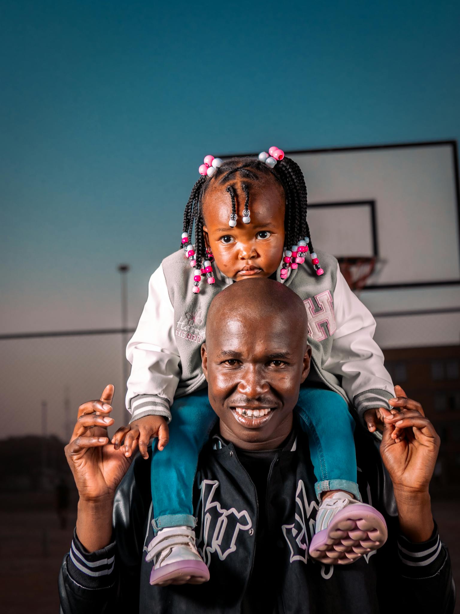 A joyful father and daughter spend time together at an outdoor basketball court.