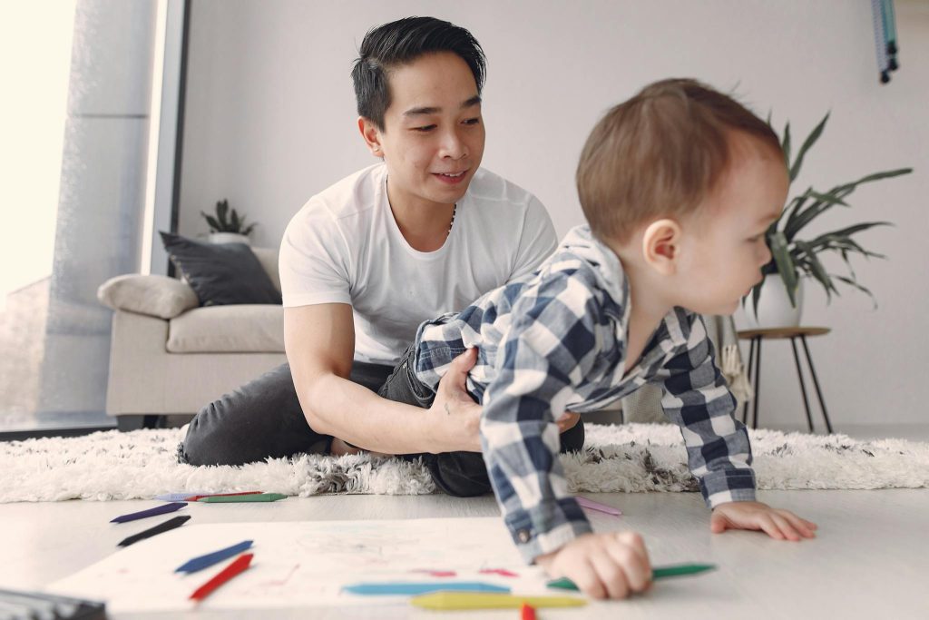 A joyful father and son bonding moment while playing on the floor at home.