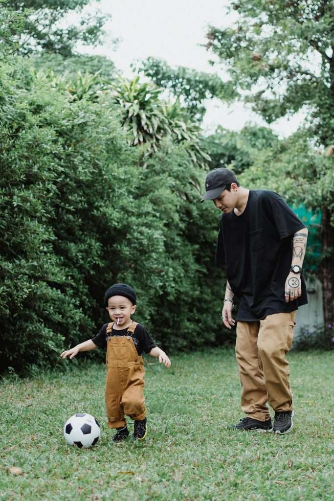 Father bonding with son over a soccer game in the lush backyard, representing family fun and happiness.